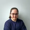 a woman with glasses sitting in front of a wall