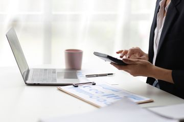 Woman sitting in front of a laptop while working on a calculator and checking  data on a spreadsheet