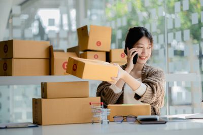 Woman talking on the phone and working with boxes