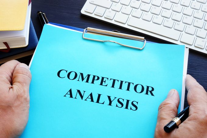 Male hands holding binder notebook titled "Competitor Analysis"