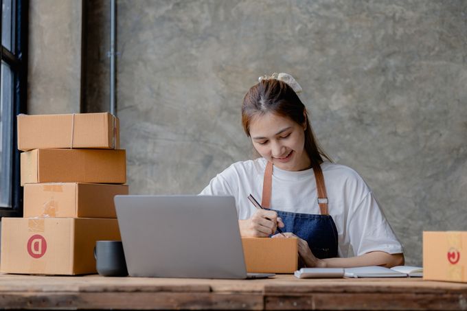 Woman sitting at a desk writing on a box
