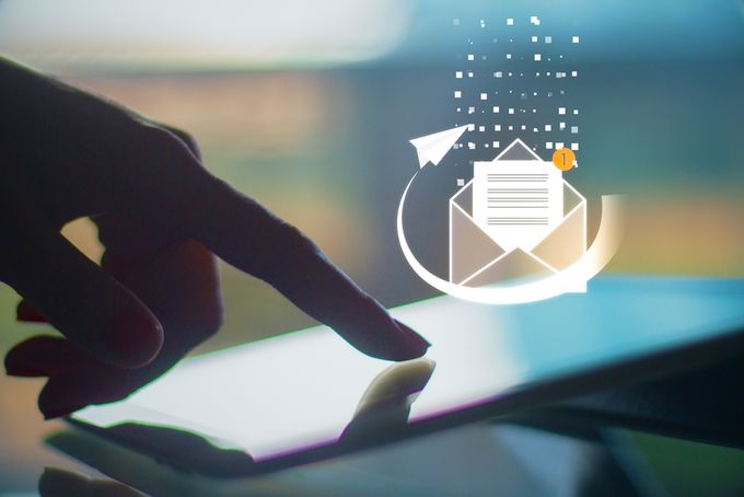 Finger touching a tablet with an image of a letter in an envelope emerging from the screen